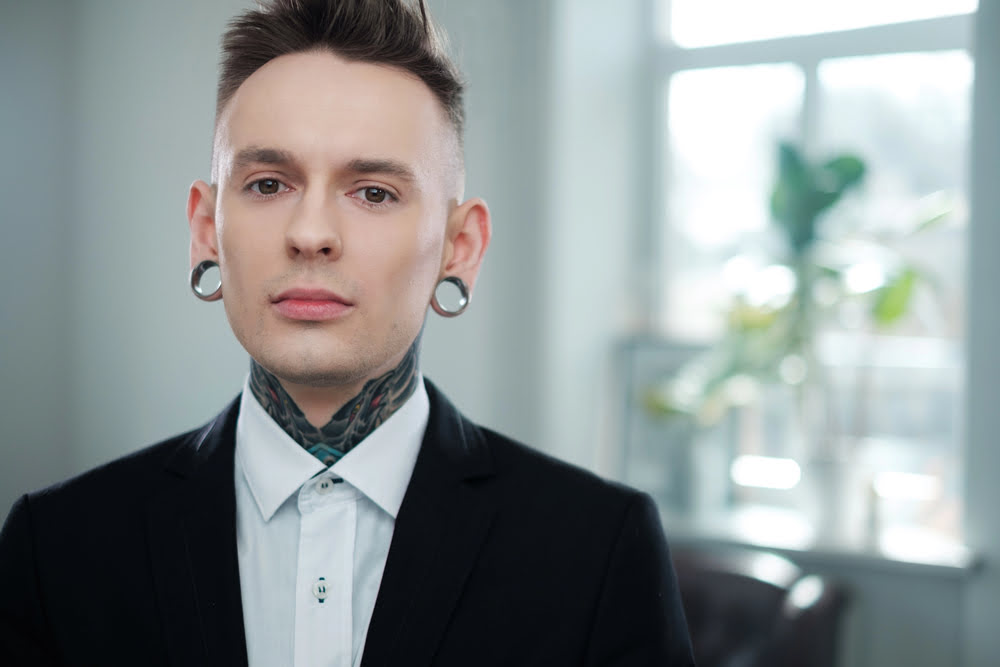 Stylischer Mann mit Flesch-Tunnel und Tattoos